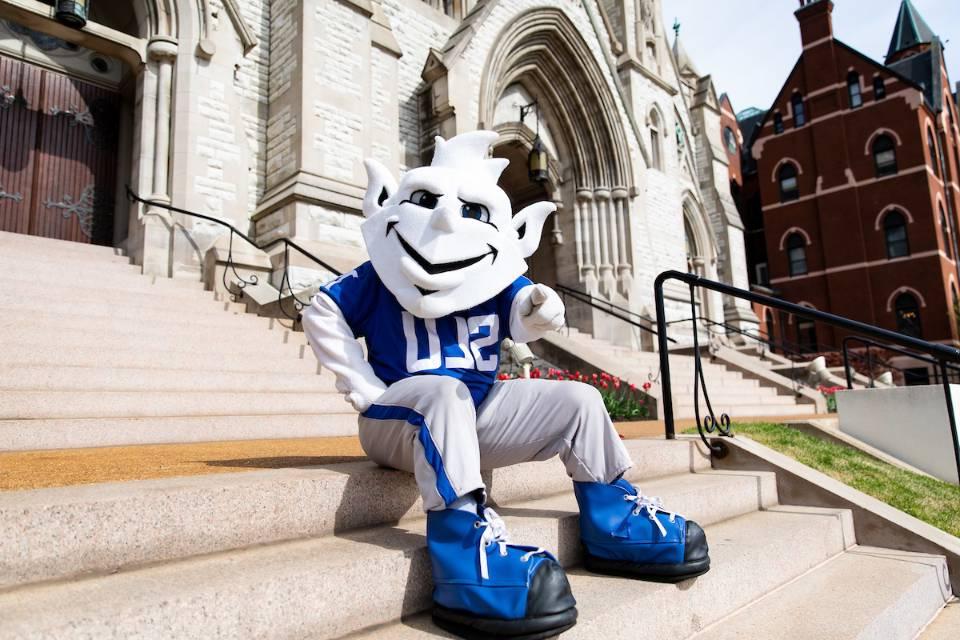 The Billiken sitting on the steps of College Church.