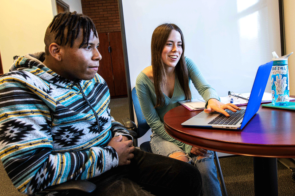 两个学生坐在桌子旁看电脑