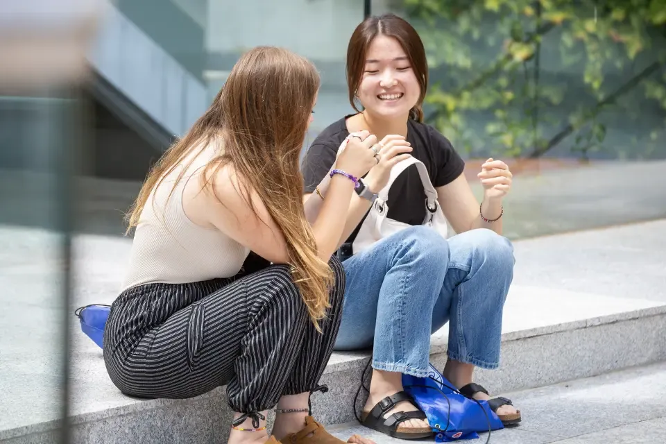 Two students talking while sitting at the PRH patio