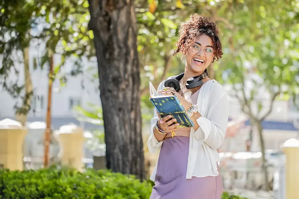 一名学生在公屋庭院拿着一本书微笑.